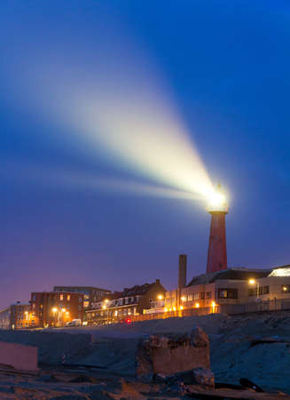 Lighthouse shines a beam of bright light into the night in Scheveningen, Netherlandsのeditorial素材