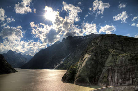 HDR image of the Grimselsee reservoir with the dam on the Grimselpass, Switzerlandの写真素材