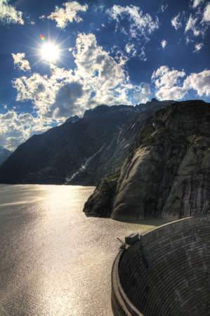 HDR image of the Grimselsee reservoir with the dam on the Grimselpass, Switzerlandの写真素材