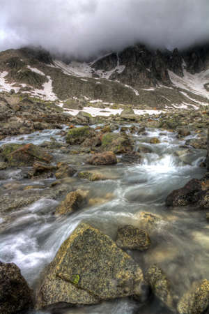 Ominous clouds above a small stream in the mountains of the Swiss Alps, HDR の写真素材