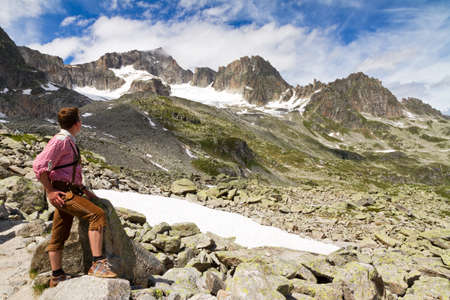 Young explorer in traditional clothinglooks at the mountains in the Swiss Alps on a sunny summer dayの写真素材
