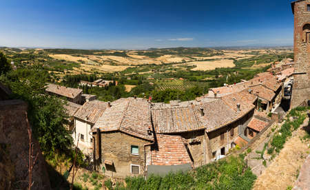 A row of traditional Tuscan houses in Italy with the beautiful landscape of tuscany behind themの写真素材