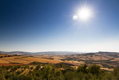 Tuscan landscape with a clear blue sky and a beautiful sun in Italyの写真素材