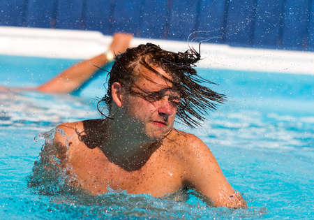 Young man shaking his head in the poolの写真素材
