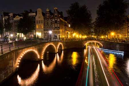 Stripes of light of a tourboat passing by on a canal in Amsterdam at nightのeditorial素材