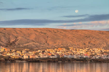 Early morning view on the small town of Pag in Croatia with the moon above it  の写真素材