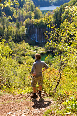 Active young man looking at a waterfall in Plitvice, Croatiaの写真素材