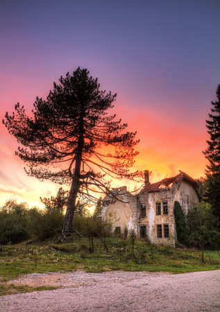 Old abandoned country house with a beautiful colored sunset in the woods near Plitvice, Croatia の写真素材