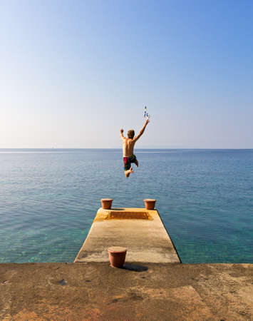 Running of a pier jumping into the sea being free in summerの写真素材