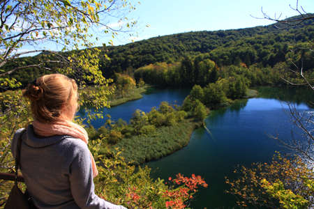 Beautiful woman looks out over a lake  park Plitvice in Croatia in autumnの写真素材