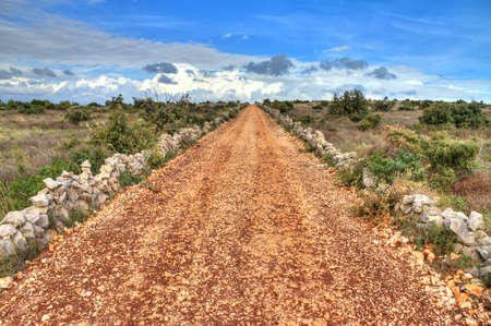 Country road up a hill leading towards a beautiful cloudscapeの写真素材