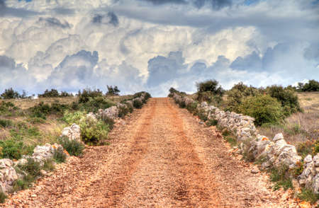 Country road up a hill leading towards a beautiful cloudscapeの写真素材