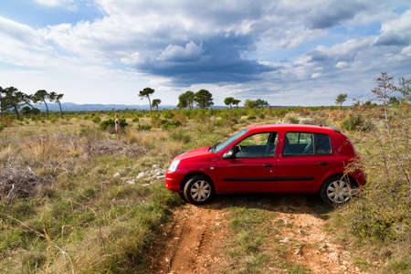 Beautiful landscape with some trees and a red car in Croatiaのeditorial素材