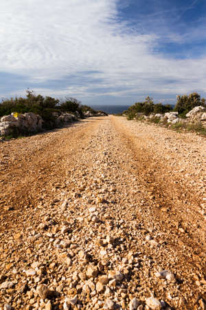 Country road down a hill leading towards the seaの写真素材