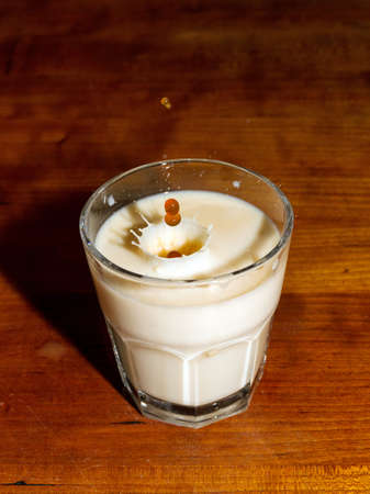Drops of coffee fall into a glass of milkの写真素材