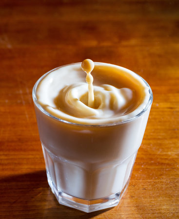 Drops of coffee with milk fall in a glass of milk, high speed