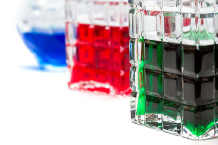 Crystal bottles with liquid in different colors  against a white backgroundの写真素材