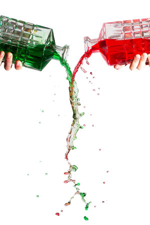 Crystal bottles pouring red and green liquid against a white backgroundの写真素材