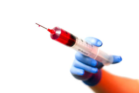 Big syringe with red liquid ready to vaccinate an arm or take bloodの写真素材
