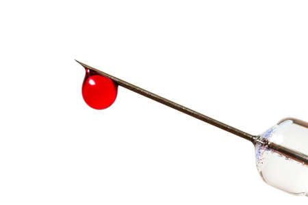 Close up image of a drop of red liquid on the needle of a syringe against a white backgroundの写真素材