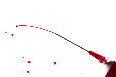 Syringe squirting red liquid against a white backgroundの写真素材