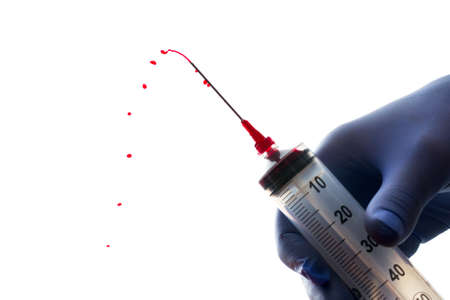 Syringe squirting red liquid against a white backgroundの写真素材
