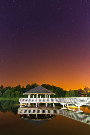 Gazebo in the middle of the lake in Vielsalm, Belgium, at night with a beautifully colored sky with lots of starsの写真素材