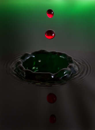 Beautiful image of a drop of red water falling into green waterの写真素材