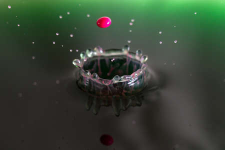 Beautiful image of a drop of pink cream falling into green waterの写真素材