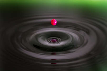 Beautiful image of a drop of pink cream falling into green waterの写真素材