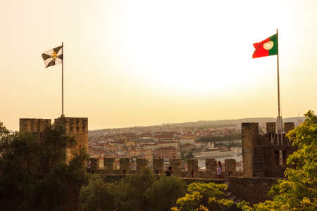 Flags on top of Castle Sao Jorge in Lisbon, Portugal, looking over the city at sunsetのeditorial素材