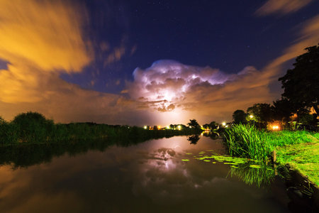 Thunderclouds and lightning reflected in the river at night in the Netherlands