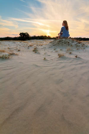 Beautiful woman at sunset on the sand plains of Kootwijkerzand in the Netherlandsの写真素材
