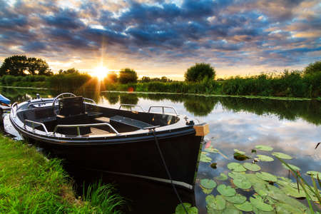 Beautiful ominous dark summer sunset at the river in Baambrugge in the Netherlandsの写真素材