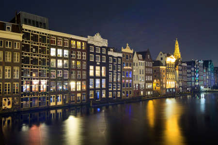 Canal houses at night at the Damrak in Amsterdam, The Netherlandsの写真素材