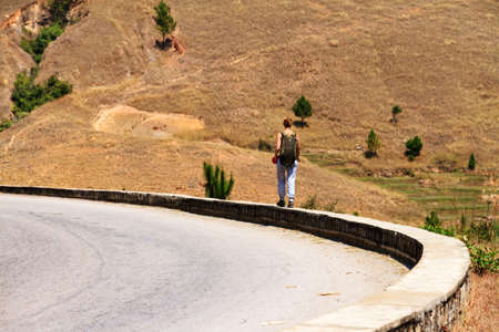 Young girl with a backpack hiking on the side of the road in Madagascarのeditorial素材