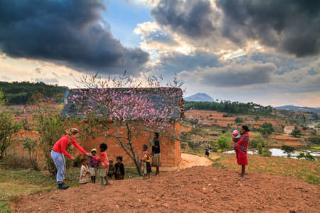 Beautiful tourist hands out candy to local kids near Antsirabe, Madagascar on September 5, 2013のeditorial素材
