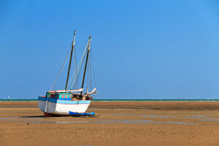 A beached sailing boat at low tide on the beach of Toliara, Madagascarの写真素材