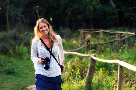 Beautiful travelling woman walking outdoors in nature with a camera on vacationの写真素材