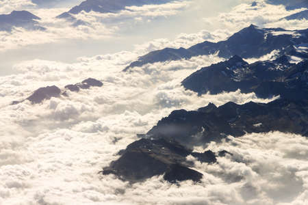 Aerial view on some mountains in the alps covered in cloudsの写真素材