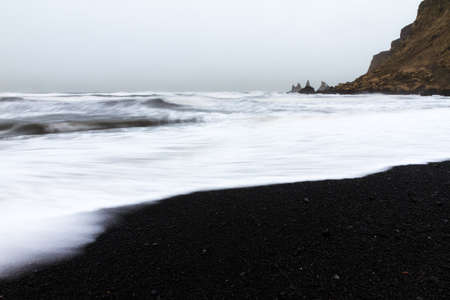 Beautiful winter view of the black sand and rough sea at the beach of Vik in Icelandの写真素材
