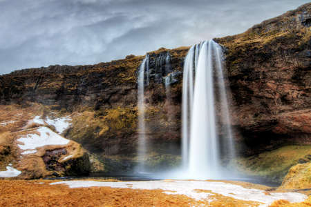 Beautiful view of the Seljalandsfoss waterfall in Iceland with ominous clouds in winterの写真素材