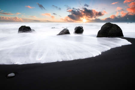 Beautiful sunset view of the black sand and rough sea at the beach of Vik in Icelandの写真素材