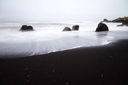 Beautiful winter view of the black sand and rough sea at the beach of Vik in Icelandの写真素材