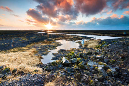 Tourist in the beautiful black volcanic river landscape of Myrdalssandur in the southern part of Iceland at sunrise in winterの写真素材