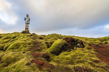 Beautiful tourist posing in the amazing volcanic mossy landscape of Eldhraun at sunrise in Icelandの写真素材