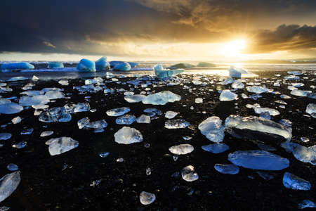 Beautiful beached chunks of ice at the beach at Jokulsarlon, Iceland, at sunset in winterの写真素材