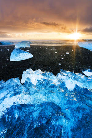 Beautiful beached chunks of ice at the beach at Jokulsarlon, Iceland, at sunset in winterの写真素材