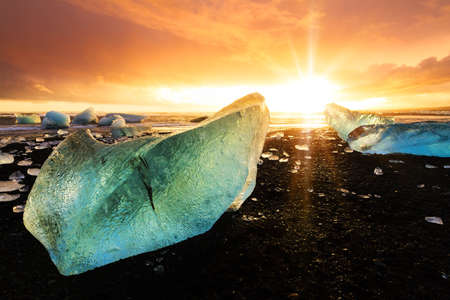 Beautiful beached chunks of ice at the beach at Jokulsarlon, Iceland, at sunset in winterの写真素材