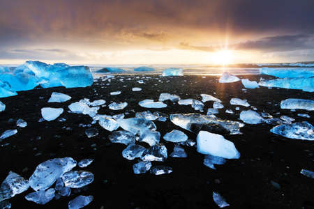 Beautiful beached chunks of ice at the beach at Jokulsarlon, Iceland, at sunset in winterの写真素材